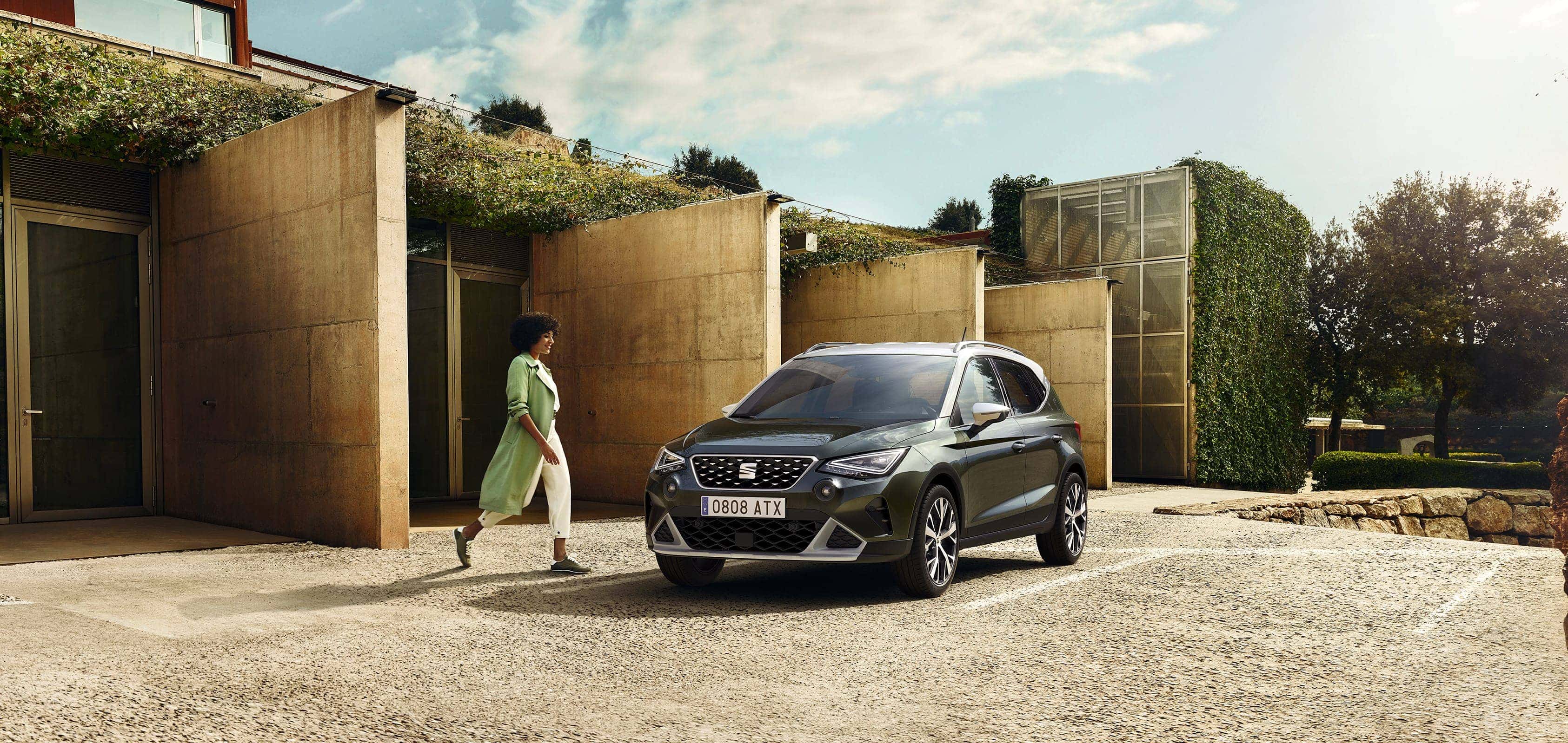 Woman walking to SEAT Arona dark camouflage colour with candy white roof